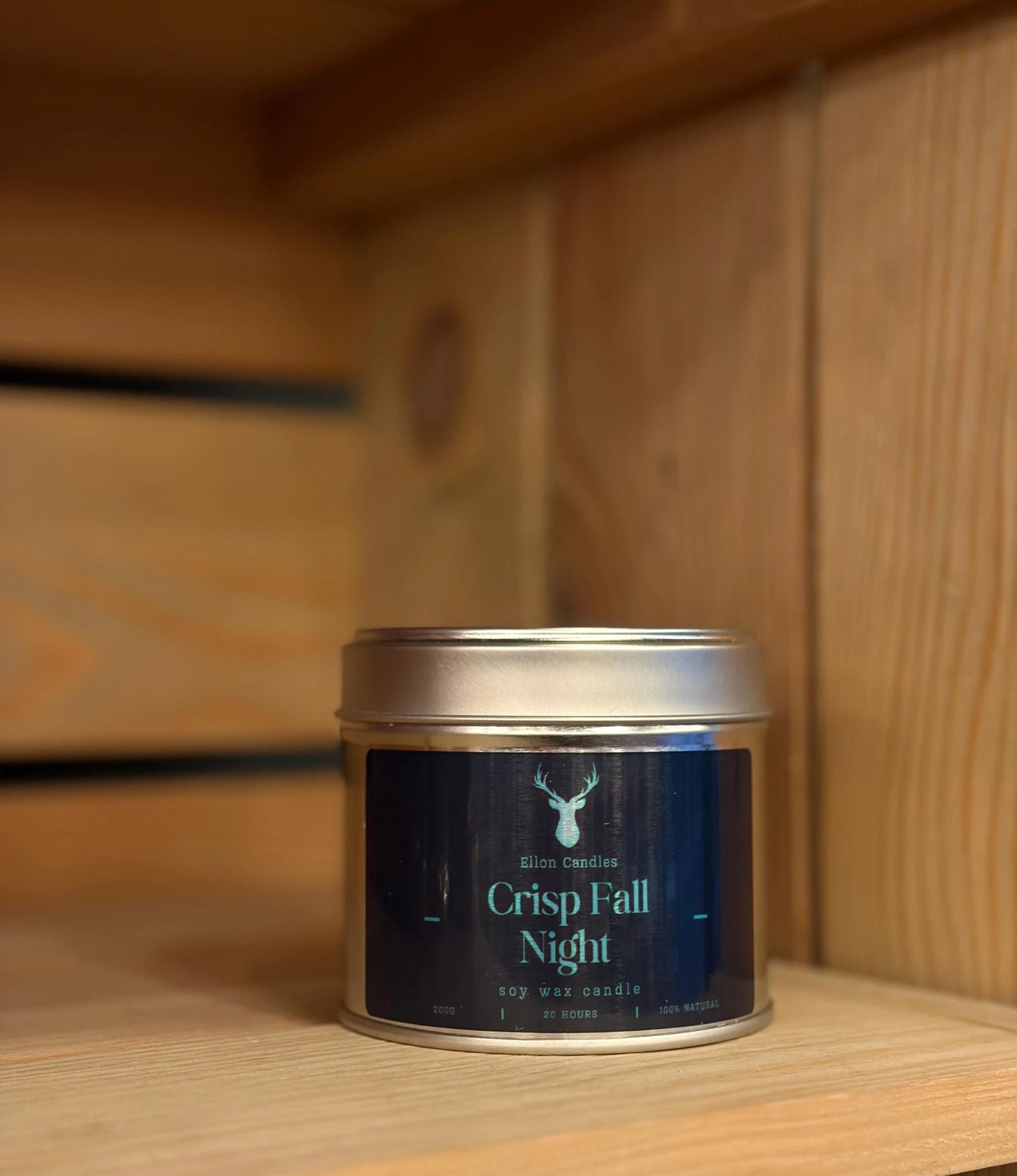 Candle tin labeled 'Crisp Fall Night' on a wooden shelf