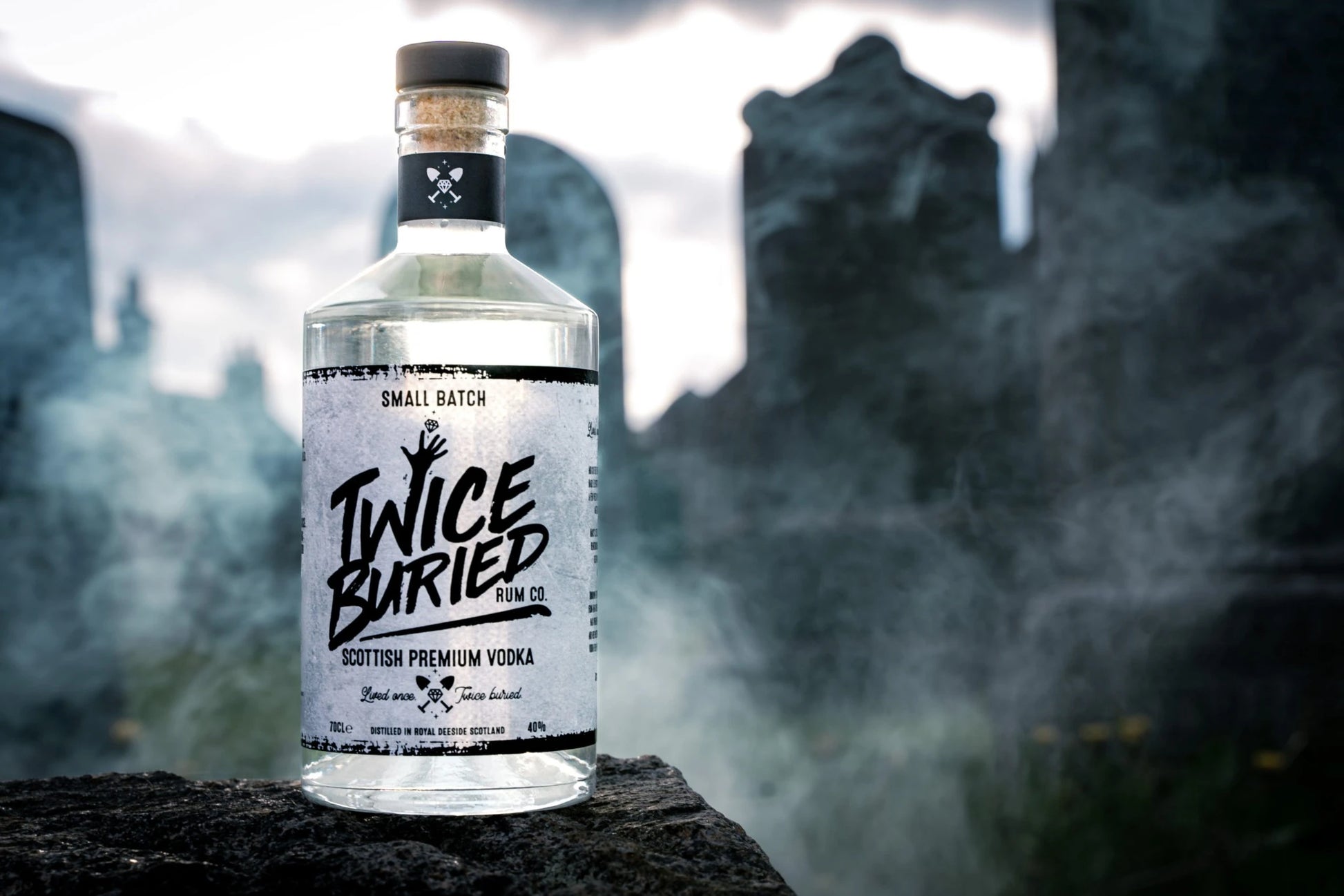 Twice Buried Premium Vodka bottle with cemetery smoke in background