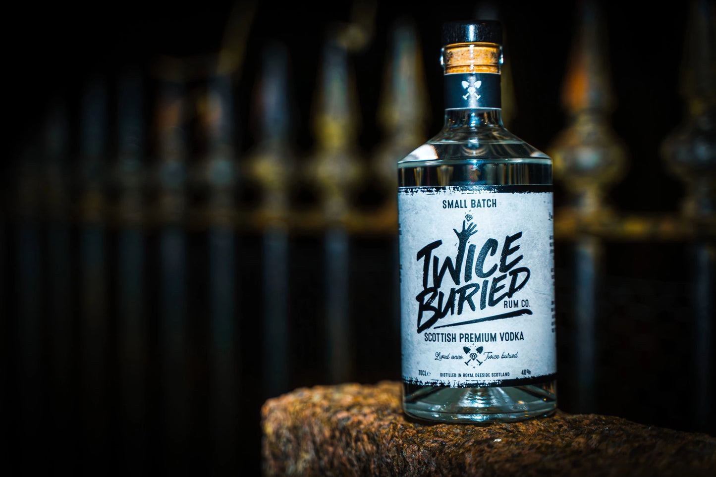 Twice Buried Scottish Vodka bottle in front of a wrought iron fence