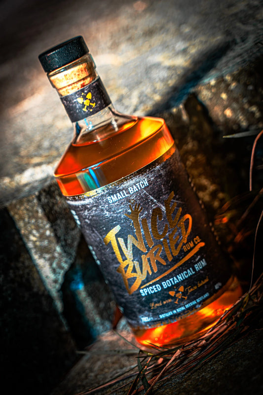 Close-up of Twice Buried Spiced Botanical Rum bottle on stone