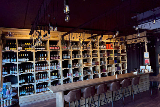 Bar area with wooden shelves stocked with bottles and a bar counter with stools.