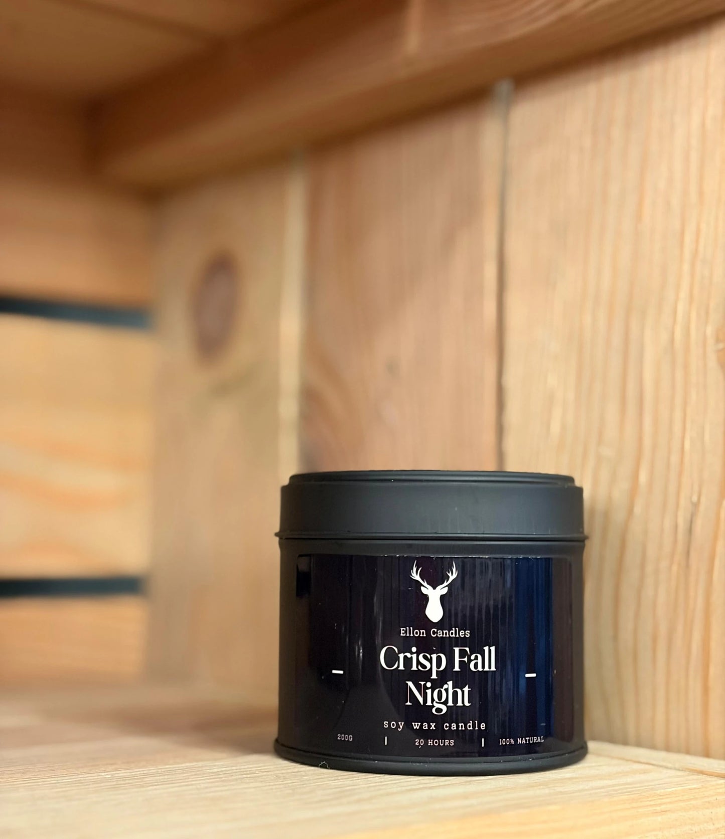 Black candle container with 'Crisp Fall Night' label on a wooden surface